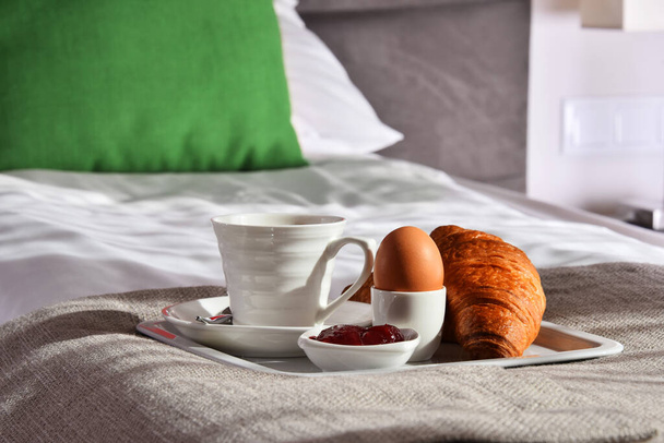 Ontbijt op dienblad op bed in hotelkamer.  - Foto, afbeelding