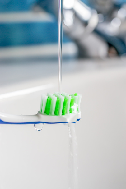 Un cepillo de dientes bajo agua corriente del grifo
 - Foto, Imagen