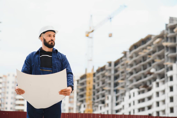 Engineer builder wearing safety vest with blueprint at construction site - Fotografie, Obrázek
