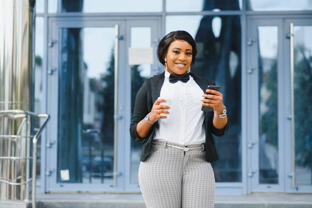 Happy successful professional posing near office building. Young African American business woman standing outside. Female business leader concept - Foto, imagen