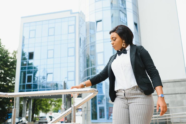 Happy successful professional posing near office building. Young African American business woman standing outside. Female business leader concept - 写真・画像