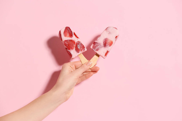 Hand with tasty strawberry ice cream on color background - Photo, Image