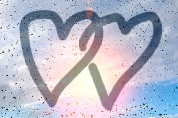 Изображение двух сердец на туманном стекле. Стеклянное окно с капельками дождя на голубом небе. Понятие любви и дружбы. Концепция валентинки. Сердце ко Дню святого Валентина
. - Фото, изображение