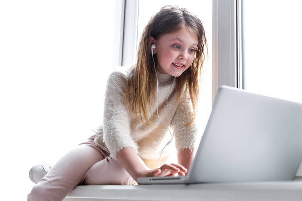A surprised teenage girl communicates via video link with friends at home, using laptop computer, having video chat. Online call friends or parents. Online education for kids. Copyspace - Photo, image