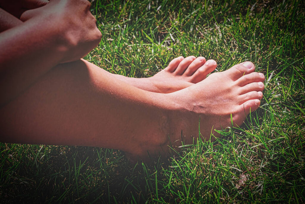 Bare feet of teen girl is set on green grass - 写真・画像