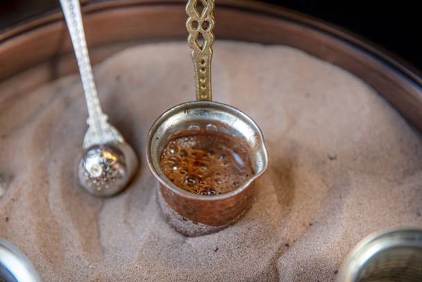 Παραδοσιακός τούρκικος καφές σε cezve παρασκευάζεται σε ζεστή άμμο. Επιλεκτική εστίαση. - Φωτογραφία, εικόνα