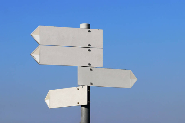 Empty directional signs in front of a blue sky - Photo, Image