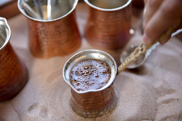 Traditional turkish coffee in cezve prepared on hot sand. Selective focus. - Photo, Image