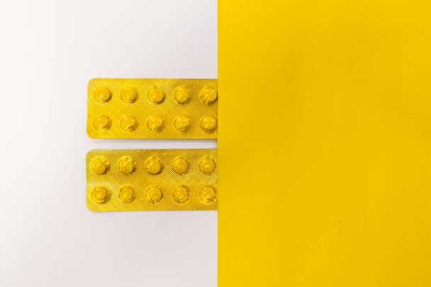 Stock photo of tablets in yellow blister packaging on white and yellow and white background. There is nobody on the picture. - Foto, Bild