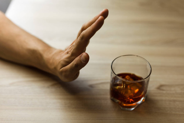 Τα χέρια κλειδώνουν ένα ποτήρι ουίσκι για να σταματήσουν να πίνουν. Αλκοολισμός. Σταμάτα τον εθισμό στο αλκοόλ. Προσθήκη στο αλκοολούχο ποτό. - Φωτογραφία, εικόνα