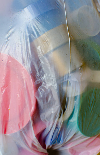 grupa wielobarwnych plastikowych osłon butelki w plastikowej torbie, zapakowana do recyklingu, faktura z tworzywa sztucznego, makro zbliżenie, obraz pionowy - Zdjęcie, obraz