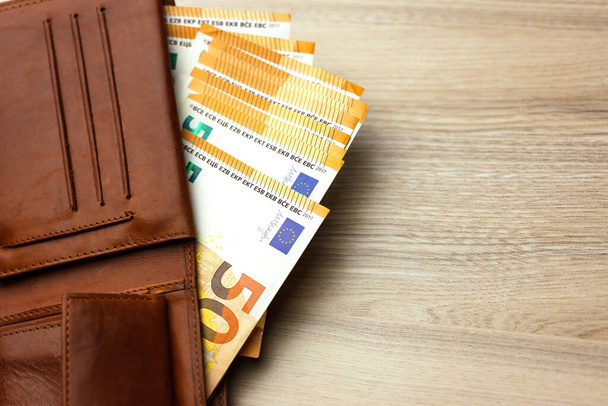 Portefeuille bourré de billets en euros sur la table en bois. Portefeuille en cuir rembourré. Euro Bills in Wallet. - Photo, image