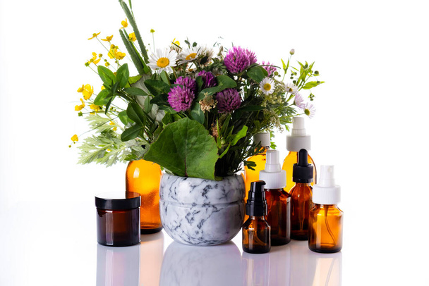 Vadvirágok márványhabarcsban és gyógyszeres üvegben illóolajjal, kozmetikai olajokkal, aromaterápiával, fitoterápiával, alternatív gyógyászattal, természetes bőrápolással. - Fotó, kép
