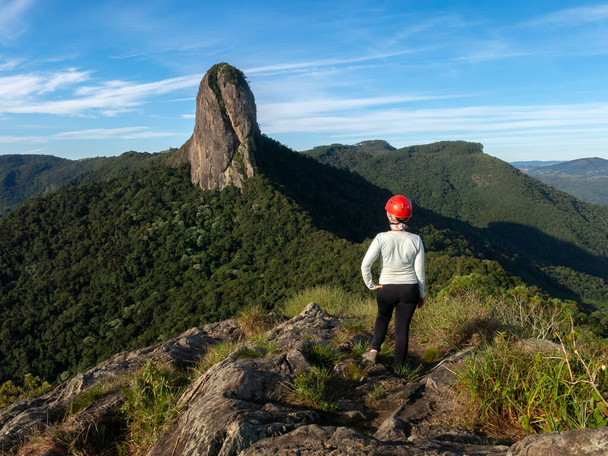 Дівчинка у шоломі дивиться на скелясту гору з вершини гори - Педра - ду - Бау. - Фото, зображення