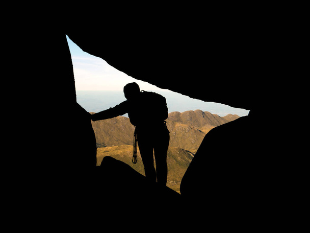 Silhouette arrampicatore all'interno di rocce con montagne sullo sfondo - Foto, immagini