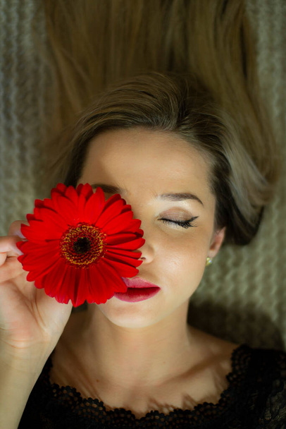 Портрет девушки с красным цветком герберы. - Фото, изображение