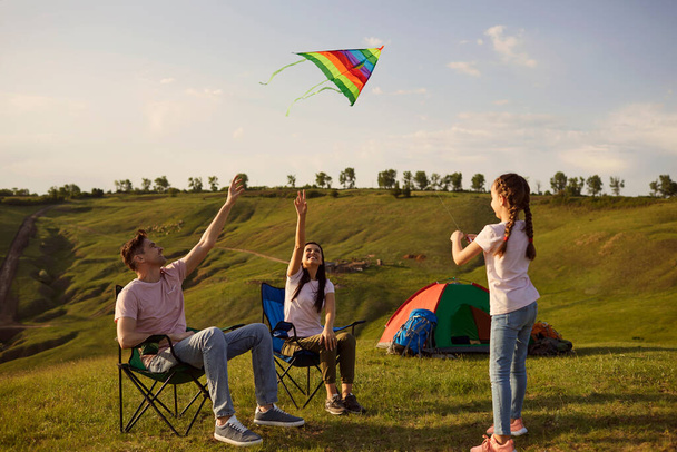 Happy family tourist on a campsite have fun playing with a kite on nature in summer. - Foto, imagen
