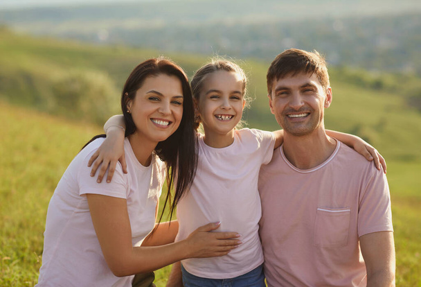 Smiling family hugs on the background of nature in summer. - Foto, afbeelding