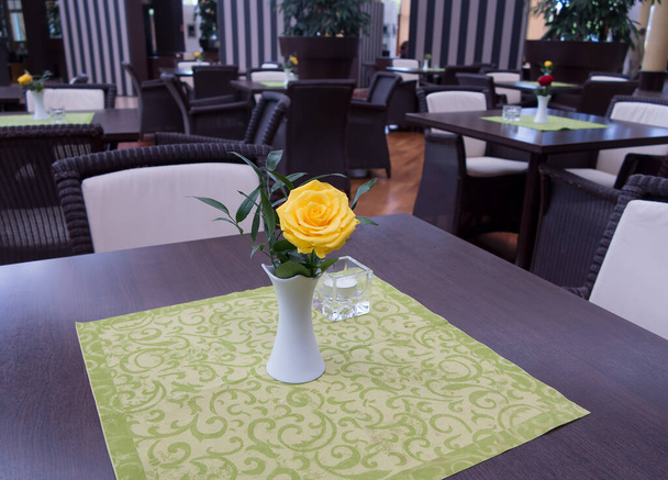 Kapalı restoran masaları ve çiçek süslemeli sandalyeler. - Fotoğraf, Görsel