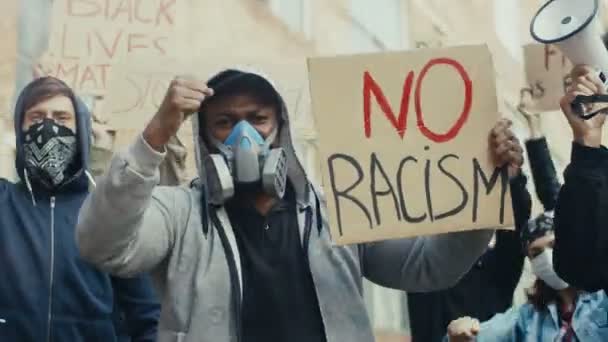 Jeunes hommes de races mixtes portant des masques à gaz portant des affiches contre le racisme dans la rue. Les gars multiethniques dans les respirateurs à la manifestation aux États-Unis contre la brutalité policière. Grève urbaine pour la liberté. - Séquence, vidéo