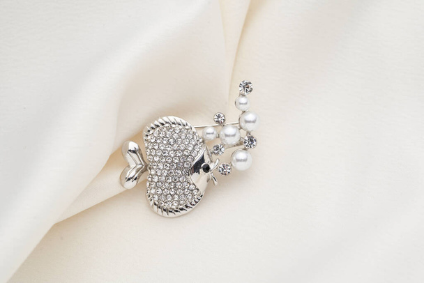 Broche de plata con forma de pez, con pequeños diamantes, aislado sobre fondo blanco
 - Foto, imagen
