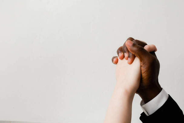 The hand of a black man grips the white female hand tightly. Friendship and support between different nationalities and religions. - Photo, Image
