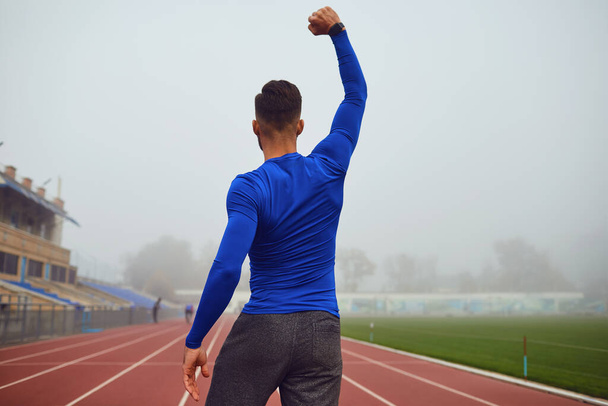 The guy the athlete raised his hands up at the stadium in the fog. - Valokuva, kuva