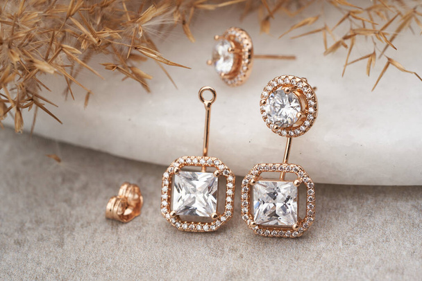 Boucles d'oreilles dorées isolées, avec cristaux blancs et diamants. - Photo, image