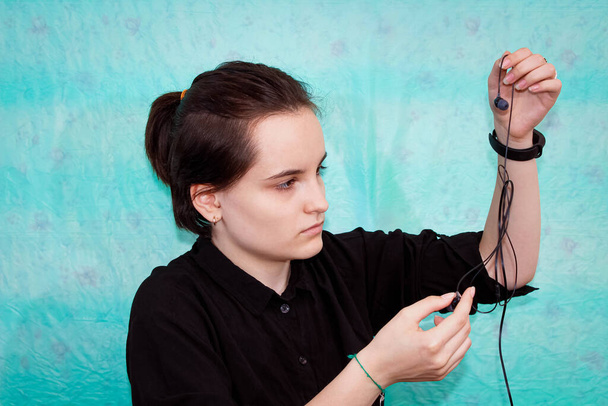Een tienermeisje probeert de draden van haar koptelefoon los te maken. Sluiten.. - Foto, afbeelding
