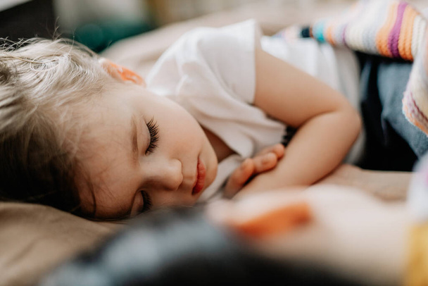 Portrait of a little blond girl sleeping in her crib. Concept of healthy regular daytime sleep for children - Photo, image