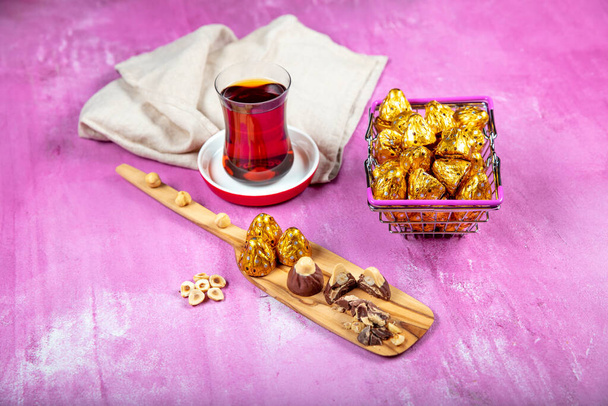 Σοκολάτα φουντουκιού; Σοκολάτα φουντουκιού είναι τυλιγμένο σε χρυσό φύλλο, σε λιλά ξύλινο φόντο. Eid al-Fitr (Γιορτή του Ραμαζανίου) έννοια. - Φωτογραφία, εικόνα