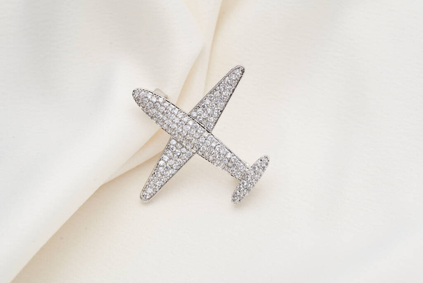 Ασημένια καρφίτσα σε σχήμα αεροπλάνου, με μικρά διαμάντια, απομονωμένη σε λευκό φόντο - Φωτογραφία, εικόνα