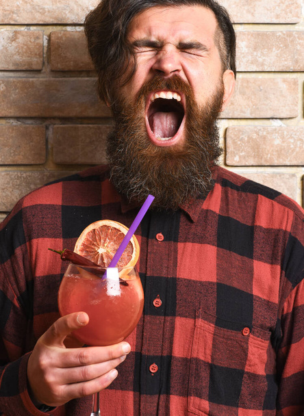Man holds alcohol cocktail on brick wall background. - Photo, image