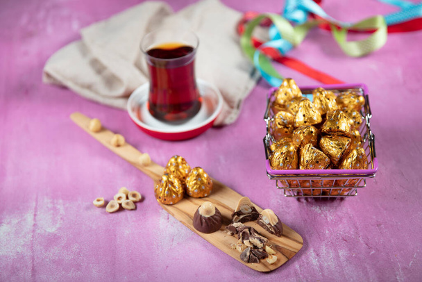 Σοκολάτα φουντουκιού; Σοκολάτα φουντουκιού είναι τυλιγμένο σε χρυσό φύλλο, σε λιλά ξύλινο φόντο. Eid al-Fitr (Γιορτή του Ραμαζανίου) έννοια. - Φωτογραφία, εικόνα