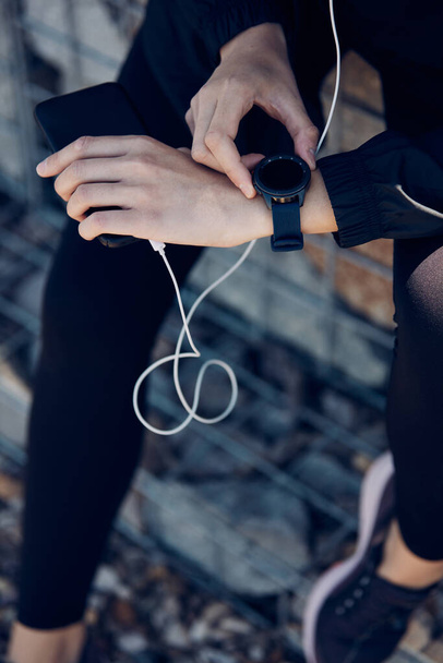 Closeup of sportswoman looking at smart watch while resting after running. - Fotografie, Obrázek