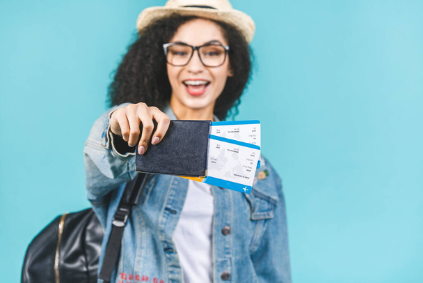 Surprised happy young african american girl isolated on blue background in studio. Travel concept. Hold passport, boarding pass tickets. - Photo, Image