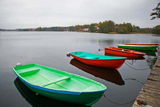 リトアニアのトラカイ・ガヴレ湖のビーチ近くにある古い木製のボート。秋と秋の時間. - 写真・画像