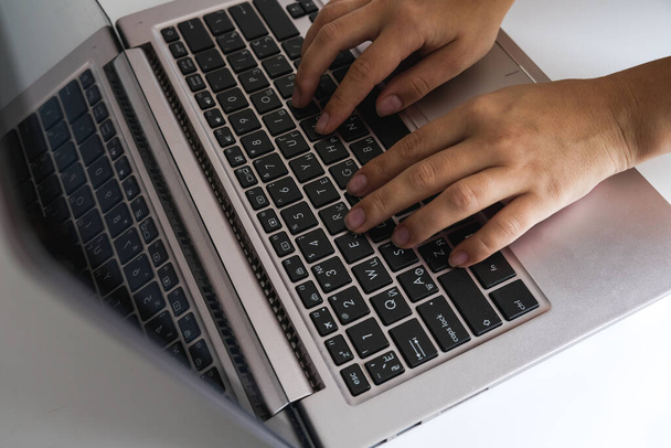 Moderne jonge vrouw die thuis werkt als freelancer. Close-up weergave van witte vrouwelijke handen typen op een laptop toetsenbord. Millennial levensstijl. Internet gebruiken tijdens sociaal isolement voor leren en werken. - Foto, afbeelding