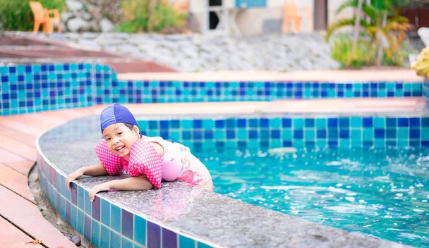 маленькая азиатская девочка с надувными рукавами играет в бассейне
 - Фото, изображение