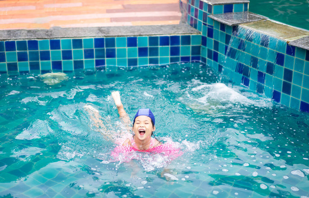 kleine asiatische Mädchen tragen aufblasbare Ärmel spielen im Pool - Foto, Bild