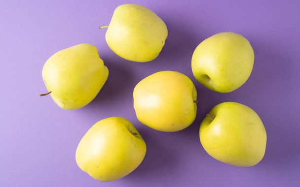 紫色の背景に黄色のリンゴ。緑のリンゴのセット。散布された熟したジューシーなリンゴ。健康的なスナック。明るい色. - 写真・画像