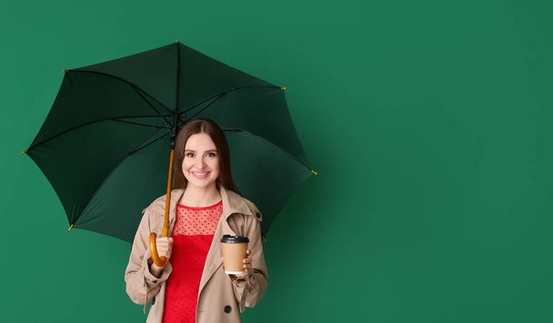 Beautiful woman with umbrella and cup of coffee on color background - Photo, Image