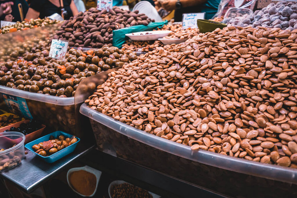 Popular local food - caramelized nuts and almond - on a stall at a farmers market indoors in Malaga, Spain. Typical spanish food choice and treat for tourists. Healthy nutritious diet decision. - Фото, изображение