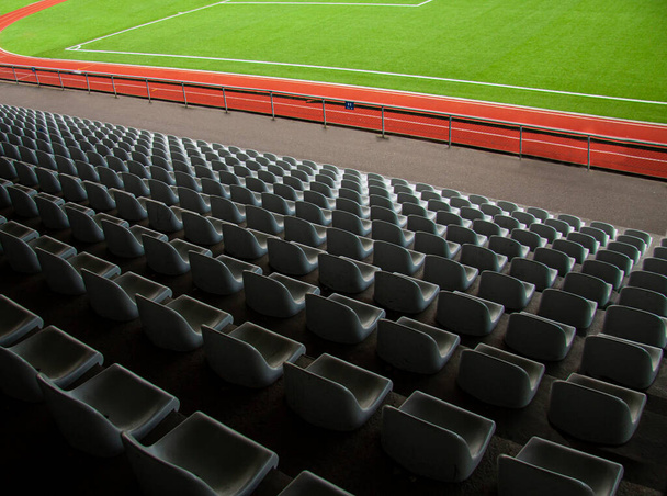 Rows of empty seats in a soccer sports stadium with green grass. Seen from above. - Photo, Image