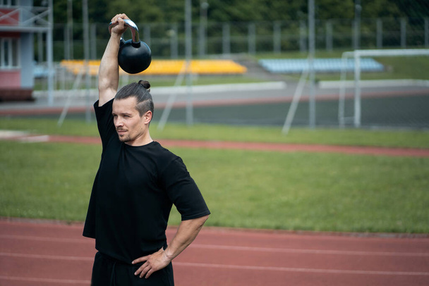 joven atleta tiene entrenamiento y hacer ejercicios deportivos con kettlebell al aire libre
 - Foto, Imagen