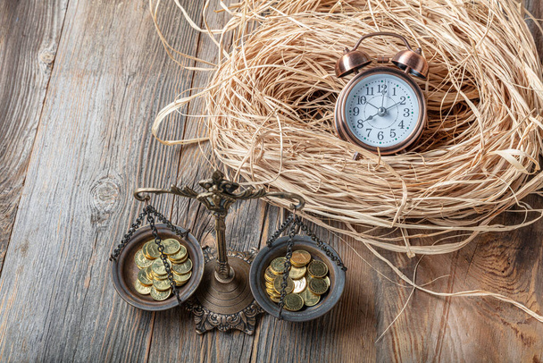 Balancing Time and Money Time ist ein Geldkonzept mit einem Haufen Münzen mit Sanduhr auf einem Holztisch. - Foto, Bild