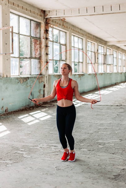 Athletic fit girl rope jumping. Fitness training, healthy lifestyle. Indoors shot in an old building - Foto, Imagen