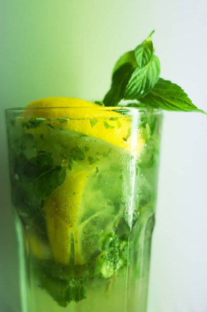 Mojito cocktail in glas, verse drank, klaar om te drinken, munt, citroen en limoen met alcohol en ijsblokjes. Groene kleur. witte achtergrond. - Foto, afbeelding