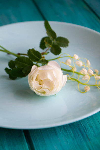 Белые нежные цветы на голубой тарелке и бирюзовом столе
 - Фото, изображение