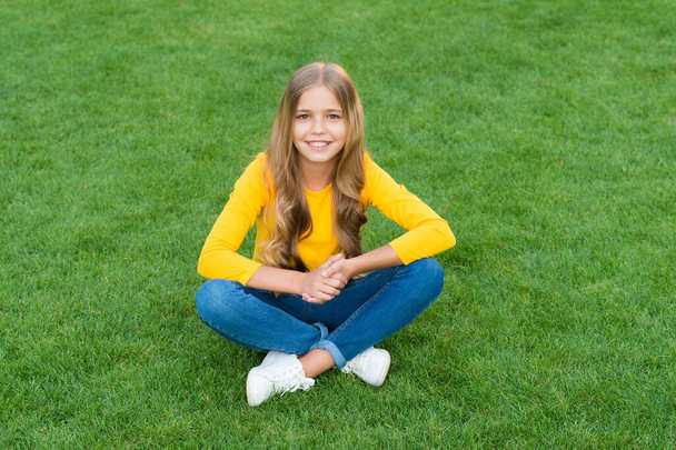 teen girl after hairdresser. relax on green grass. spring leisure time. happy childhood. kid with stylish hair. cheerful smile. happy little girl has long curly hair. kid beauty and fashion - Foto, immagini